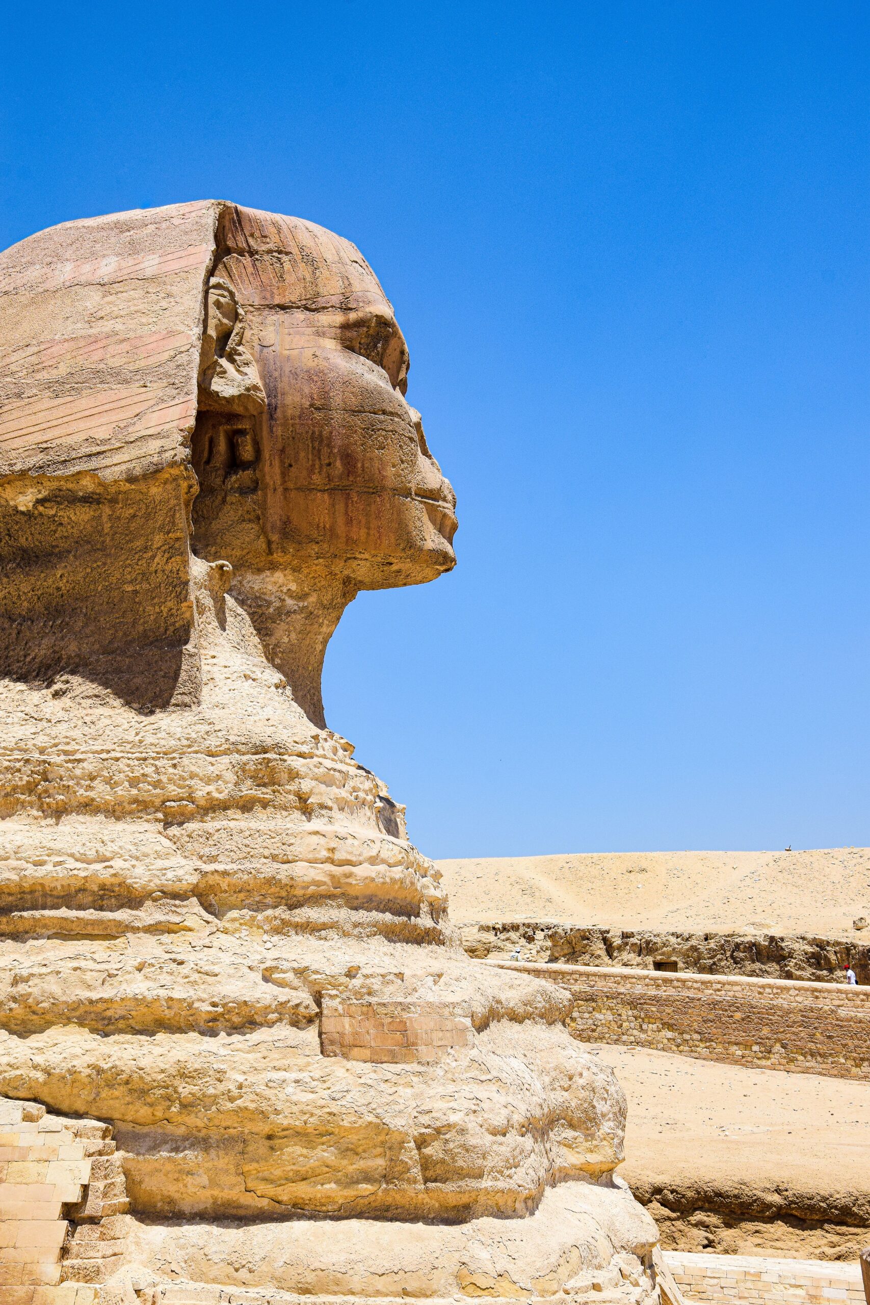 A side view of the iconic Great Sphinx of Giza against a vivid blue sky, symbolizing ancient history.