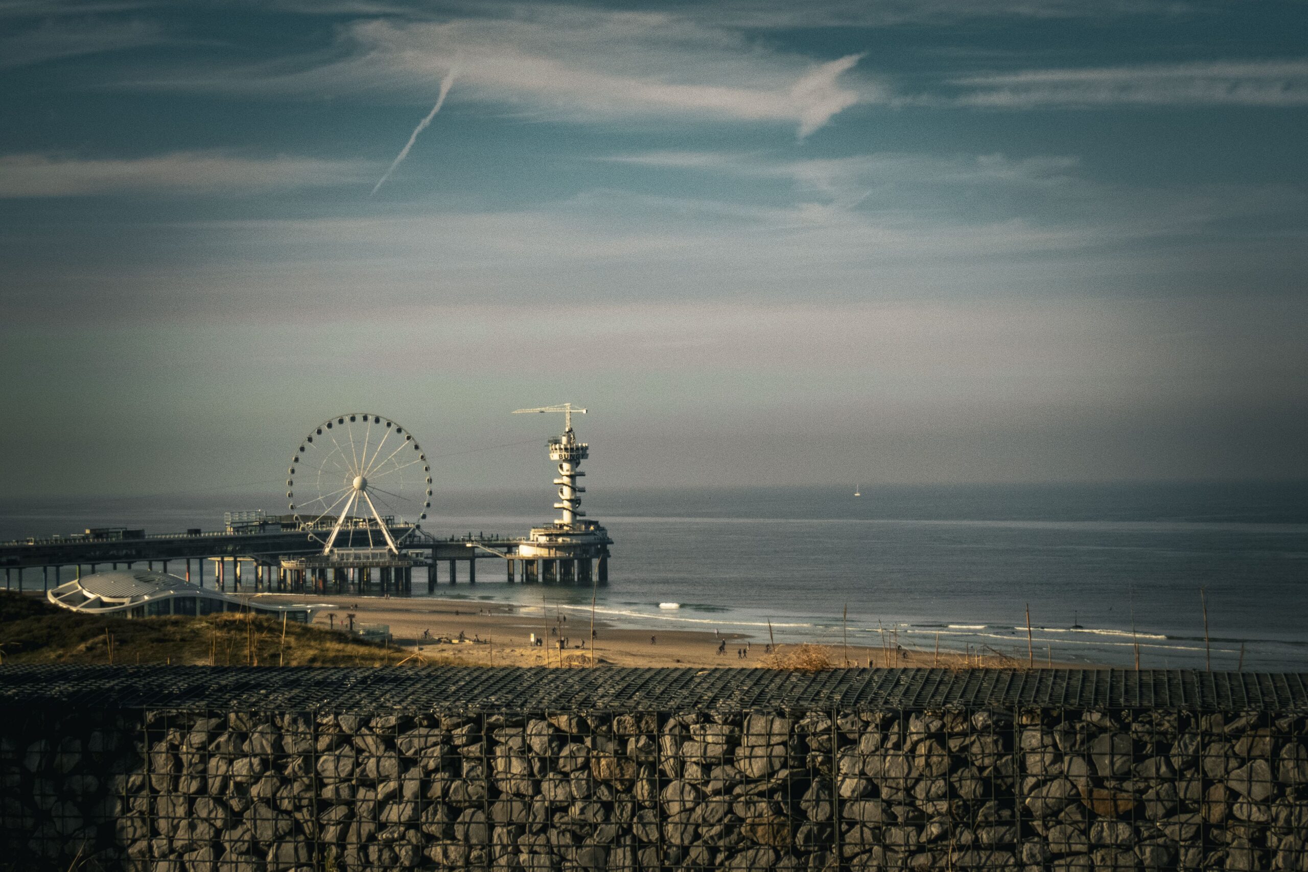 Panoramic view of Scheveningen Pier with its iconic Ferris wheel, under a serene sky.